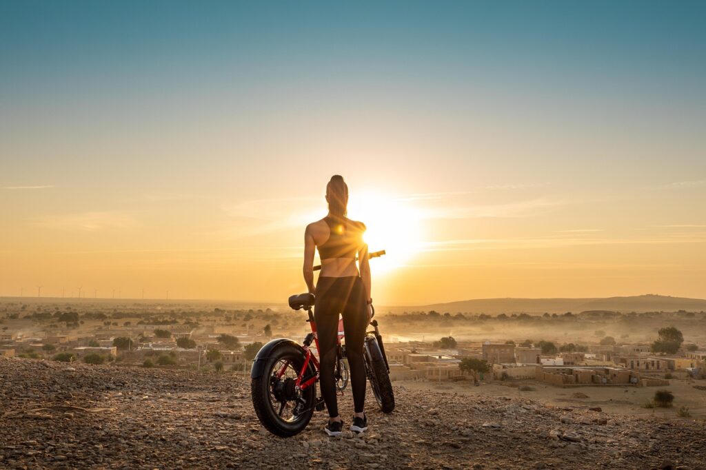 This image shows the woman with an commuter e-bike under sunset.